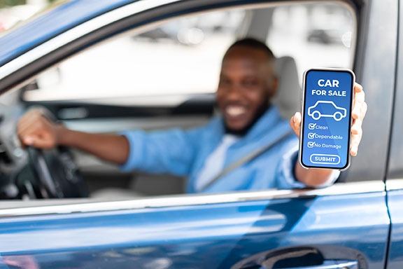 Man holds phone in his car that's recently been prepped for sale.