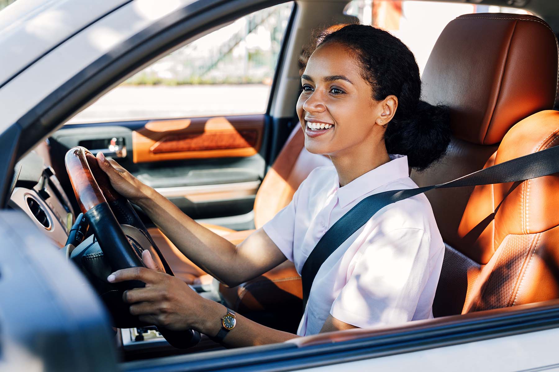 A female customer smiling and driving her car through a car wash.